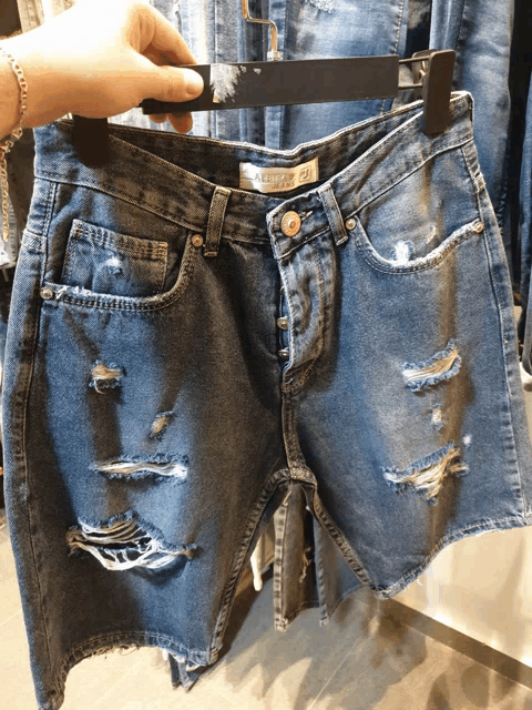 a person is holding a pair of ripped denim shorts that say ' abercrombie & fitch ' on them