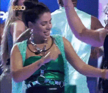 a woman in a green dress is dancing at a party with bbc on the screen