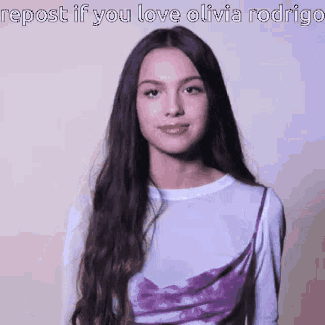 a woman with long dark hair is wearing a purple dress and a white shirt .