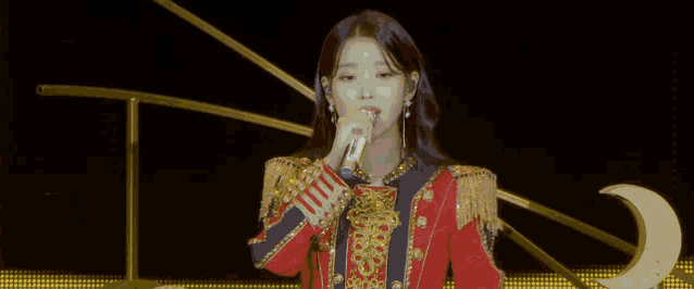 a woman is singing into a microphone on stage .