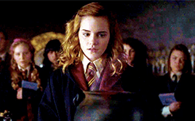 a girl in a school uniform is holding a pot in front of a group of people .