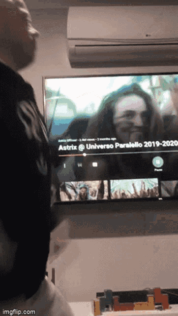 a man stands in front of a tv screen that says astrid @universo parallelo 2019-2020