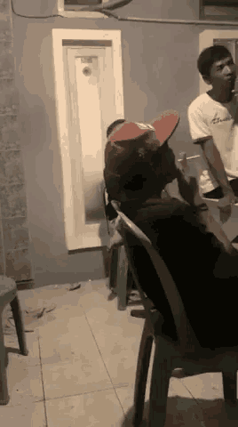 a man wearing a red hat is sitting in a chair in a room .