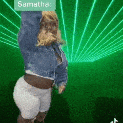 a woman in a denim jacket and white shorts is dancing in front of green lights .