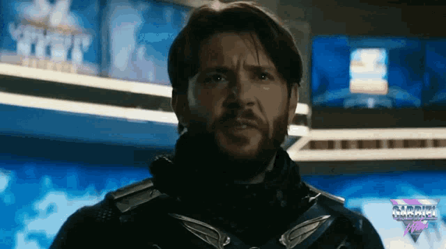 a man with a beard is standing in front of a screen that says ' marvel ' on it