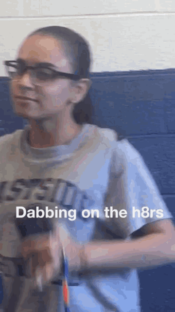 a girl wearing glasses and a shirt that says ' dabbing on the h8rs ' on it
