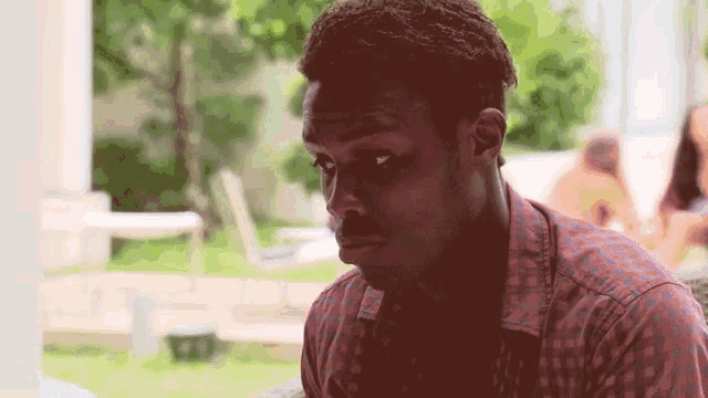 a man in a red and blue plaid shirt looks down