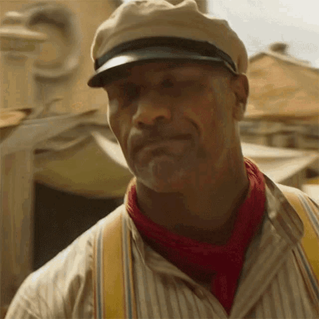 a man wearing a hat , suspenders and a red scarf is smiling .