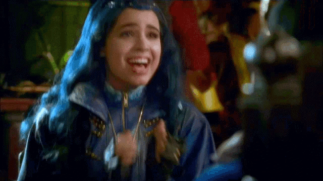 a girl with blue hair is smiling and wearing a blue jacket