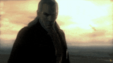 a man in a suit stands in front of a cloudy sky with the letter s on the bottom right