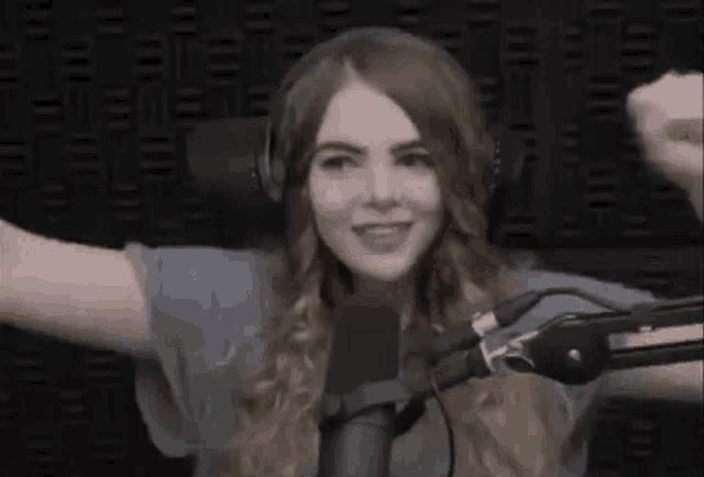 a woman wearing headphones and a microphone is standing in front of a microphone .