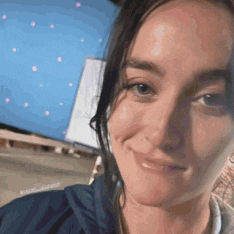 a woman is smiling and taking a selfie in front of a blue screen .