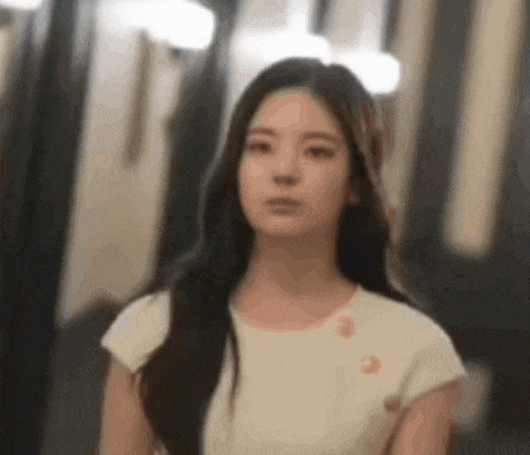 a woman in a white shirt is looking at the camera .