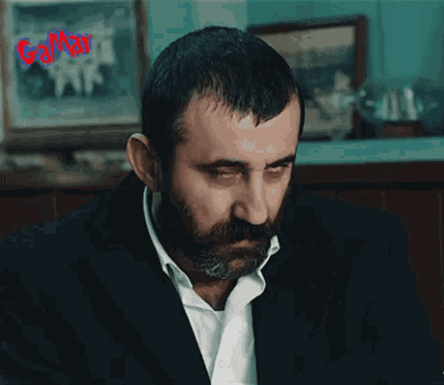 a man with a beard wearing a black suit and white shirt
