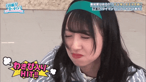 a girl with a green headband is making a funny face with her eyes closed .