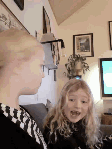 a woman and a little girl are standing in front of a television