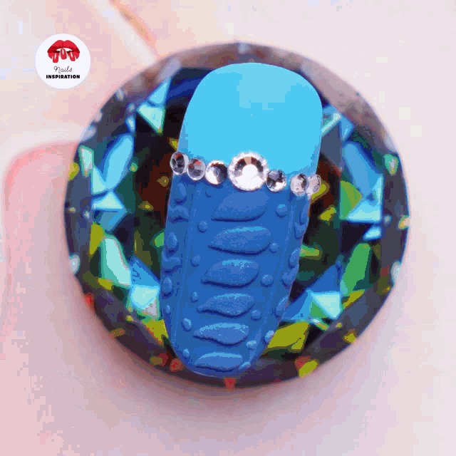 a blue object with rhinestones on it sits on top of a diamond shaped item
