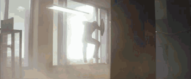 a silhouette of a person holding a shield standing in a window .