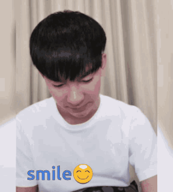 a man in a white shirt is smiling with a yellow smiley face