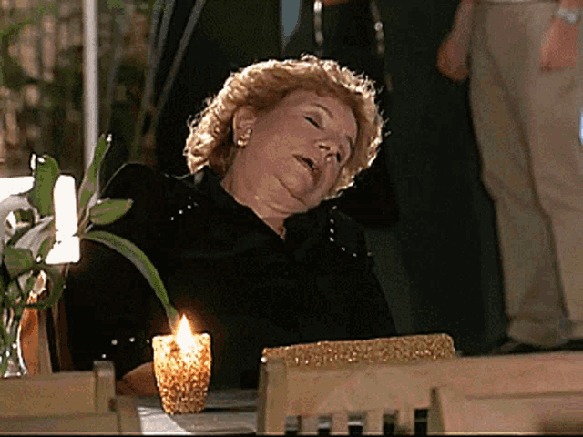 a woman sits at a table with a lit candle