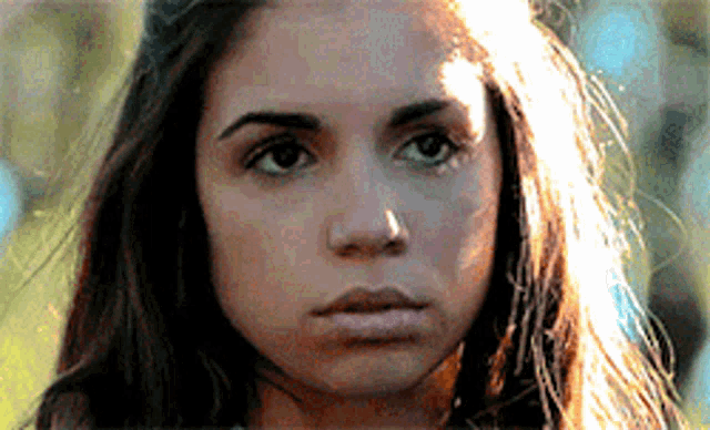 a close up of a woman 's face with the sun shining on her hair
