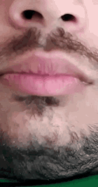 a close up of a man 's mouth with a beard and pink lips .
