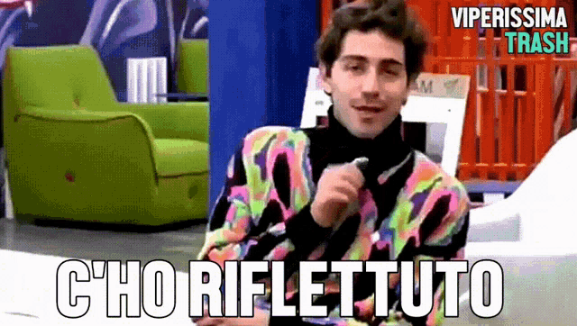 a man in a colorful sweater is talking into a microphone with the words c'ho riflettuto below him