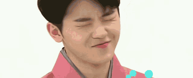 a close up of a young man wearing a pink jacket and making a funny face .