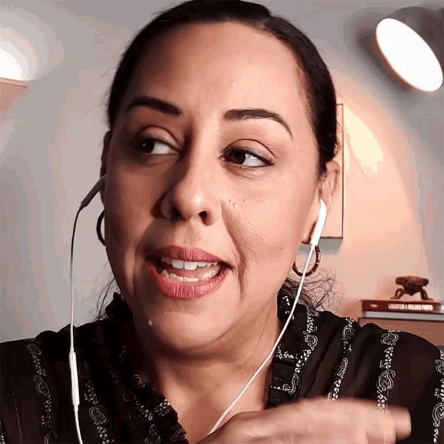 a woman wearing ear buds and a black shirt with a paisley pattern on it