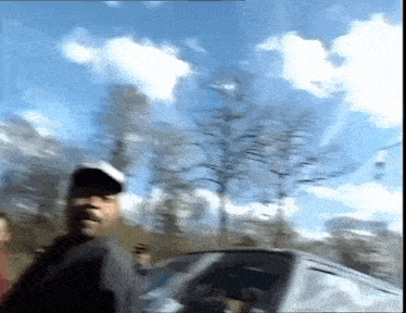 a blurry picture of a man standing next to a car with trees in the background