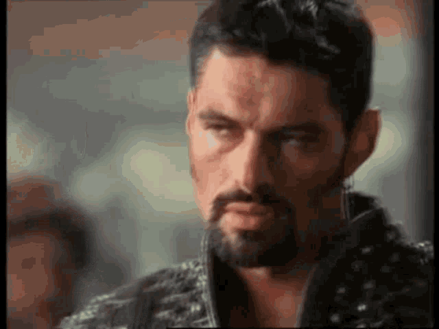 a man with a beard is making a funny face and looking at the camera .