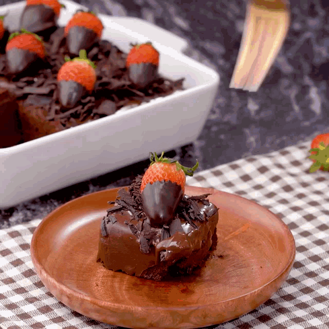 a piece of chocolate cake with strawberries dipped in chocolate on top