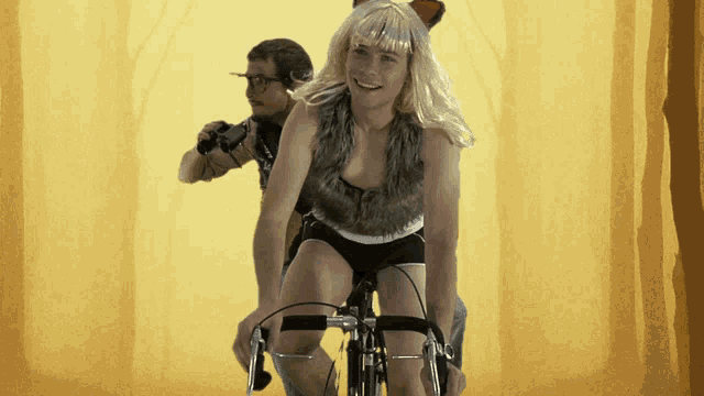 a woman in a fox costume rides a bike next to a man