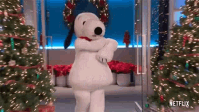 a stuffed animal dressed as snoopy is dancing in front of christmas trees .