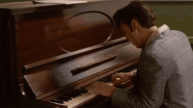 a man in a suit is playing a piano with a circle on the top of it