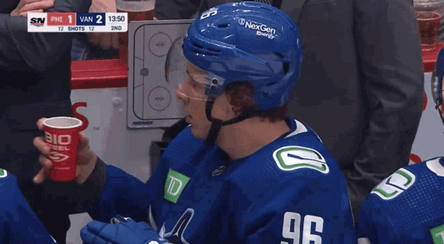 a hockey player with the number 96 on his jersey is drinking from a red cup
