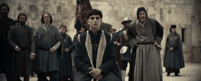 a man in a fur coat is sitting in front of a group of men