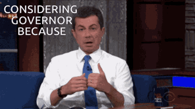 a man in a suit and tie is sitting on a couch with the words considering governor because behind him
