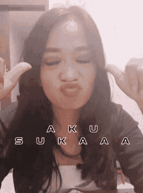 a woman is making a funny face with the words aku sukaa written on her face