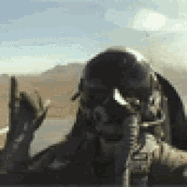a man wearing a helmet and goggles is holding a gun and giving a thumbs up .