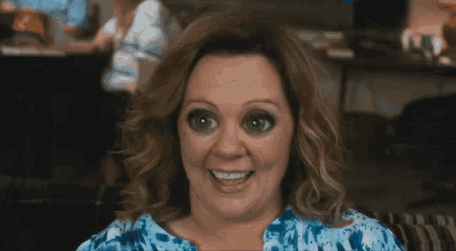 a woman with black eyes is smiling and wearing a blue shirt