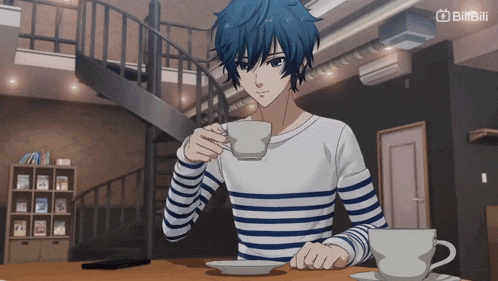 a man sitting at a table drinking a cup of coffee with a staircase behind him