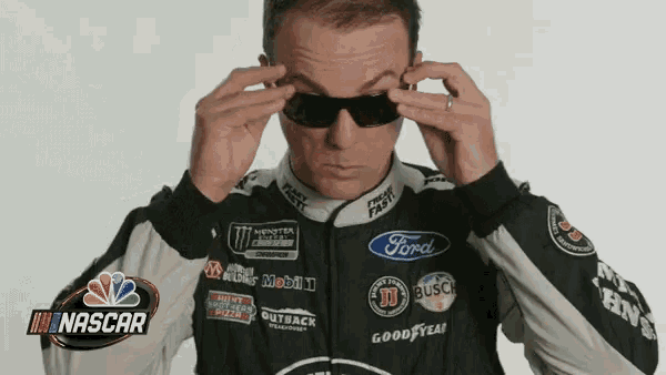 a man wearing a nascar jacket adjusts his glasses