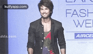a man is walking down a ramp at a fashion show .