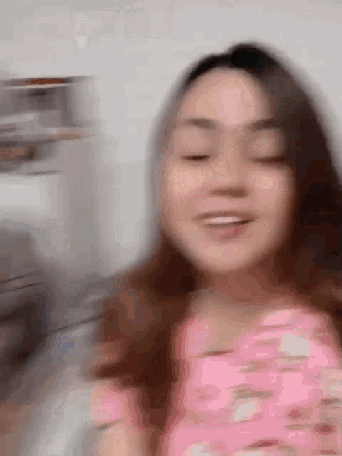 a blurry picture of a woman in a pink dress with her eyes closed
