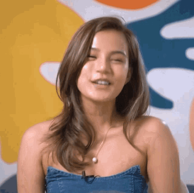 a woman wearing a denim strapless top and a pearl necklace