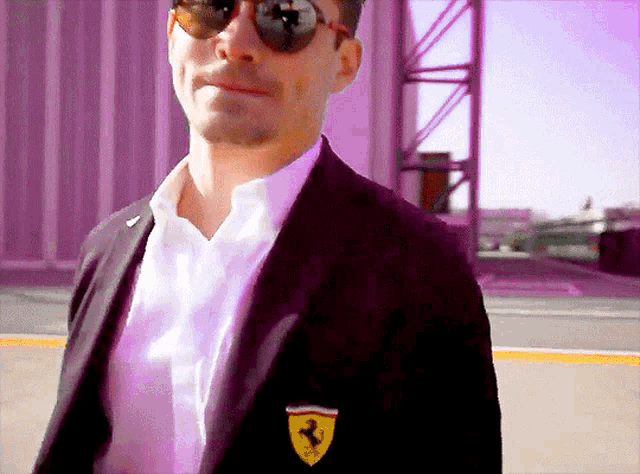 a man wearing sunglasses and a black jacket has a ferrari logo on his jacket