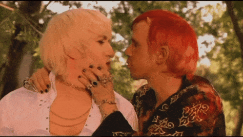 a man with horns on his head kisses another man with blonde hair