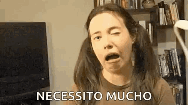 a woman with pigtails is making a funny face in front of a bookshelf .