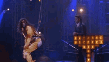 a woman is hanging from a rope in front of a cross that is on fire .